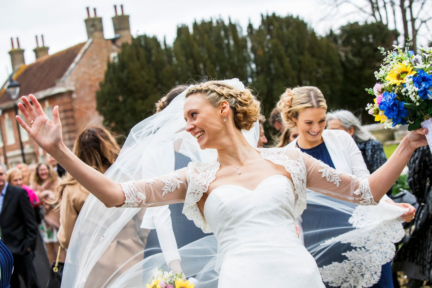 Joyful celebration outside with flowing veils and bright bouquets.