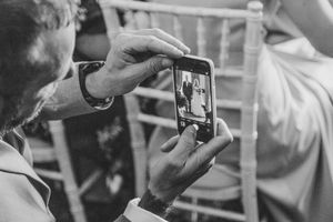 Guests taking pictures on an IPhone during a wedding ceremony
