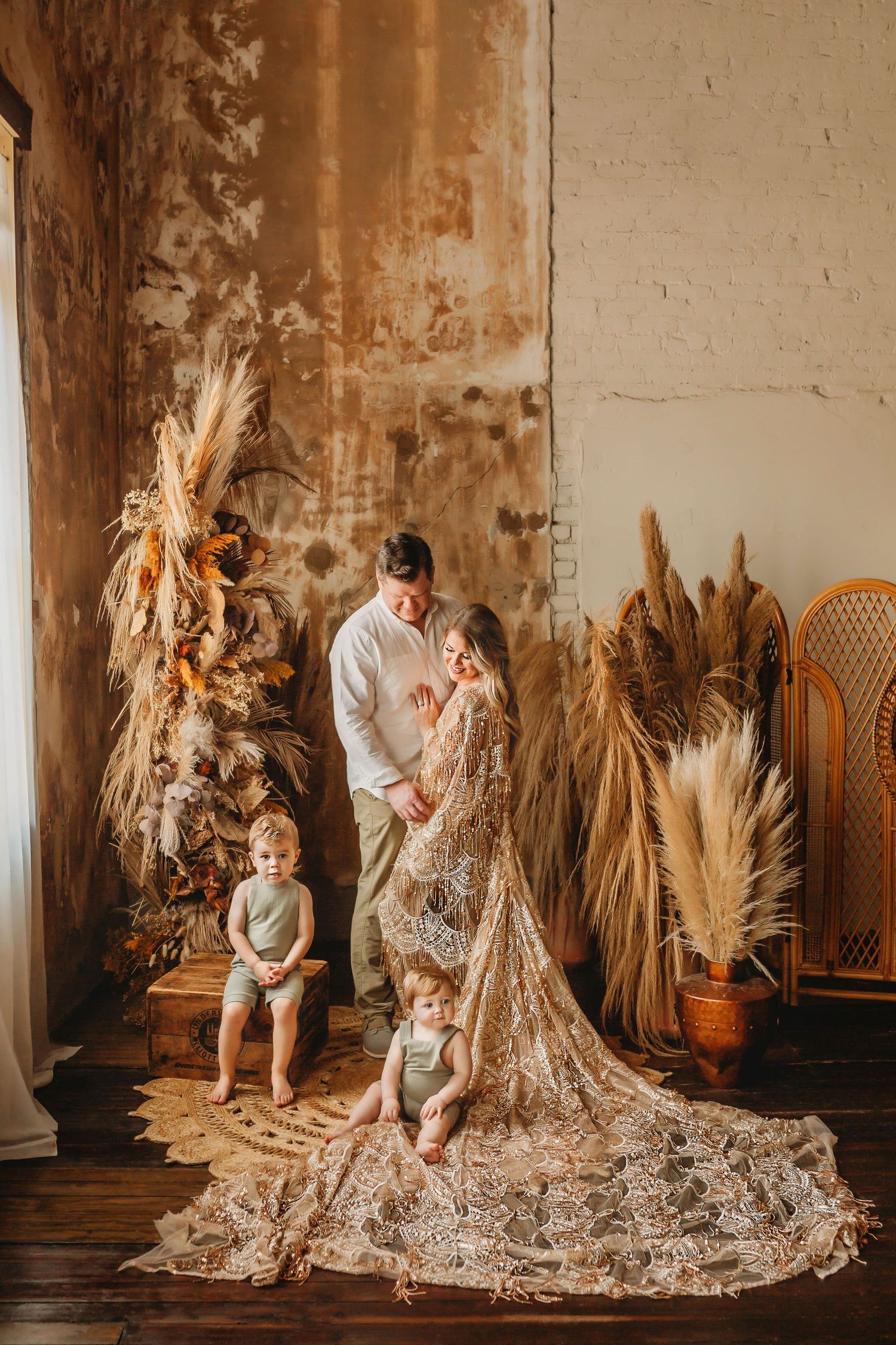 Family portrait with dried floral decor and elegant lace dress in rustic setting.