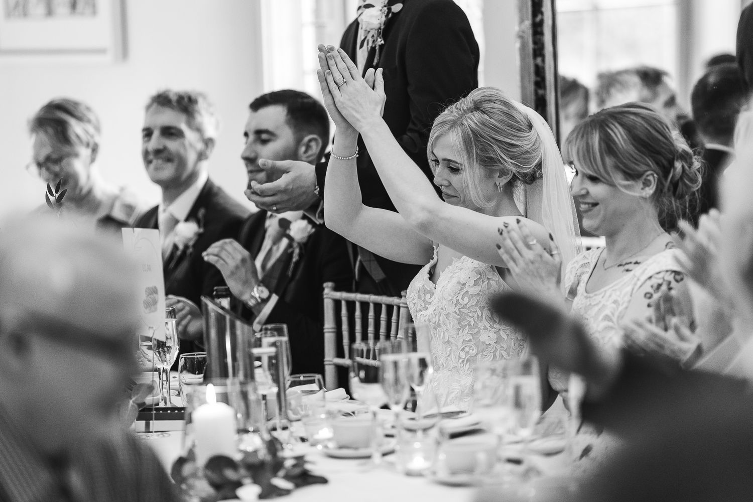 Guests raise their hands in celebration during an elegant wedding reception dinner.