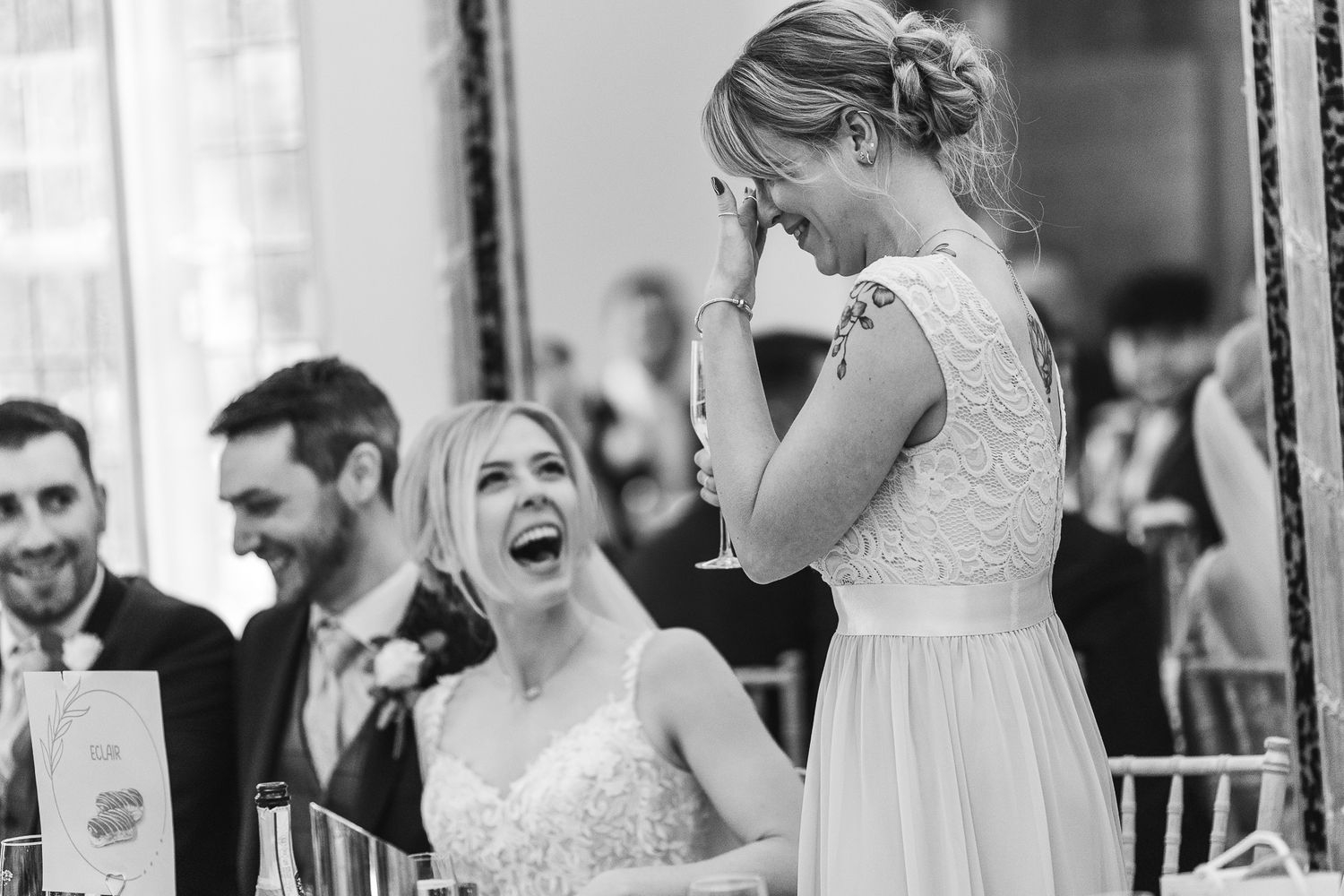 Black and white photo shows emotional reactions during wedding reception speeches.