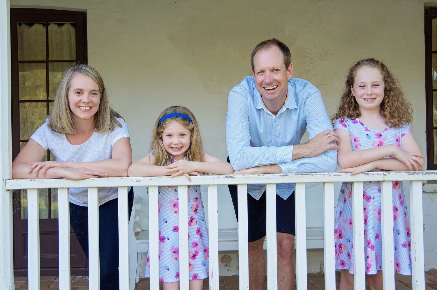family of 4 on porch smiling at camera