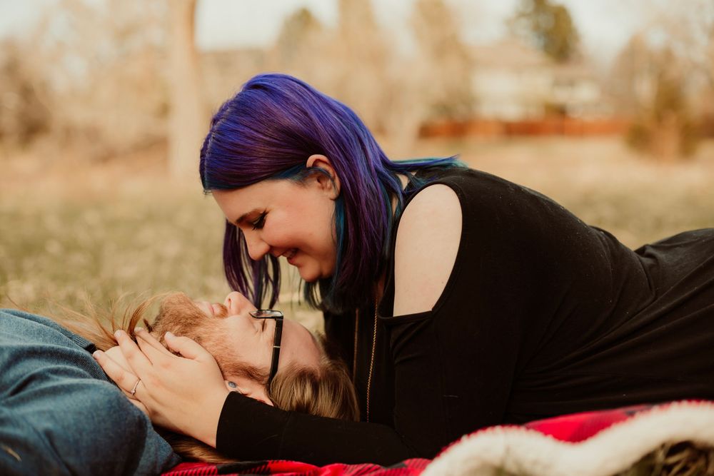 Intimate moment captured on a blanket outdoors during golden hour.
