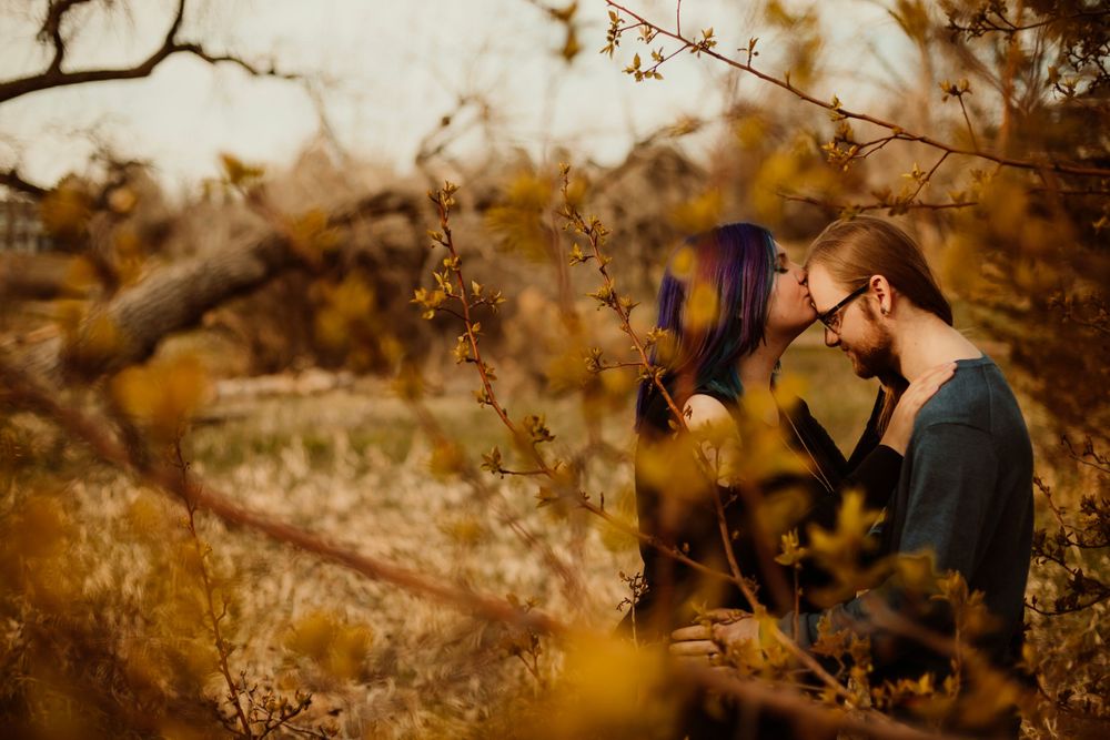 Couple sharing tender moment among autumn branches at sunset.