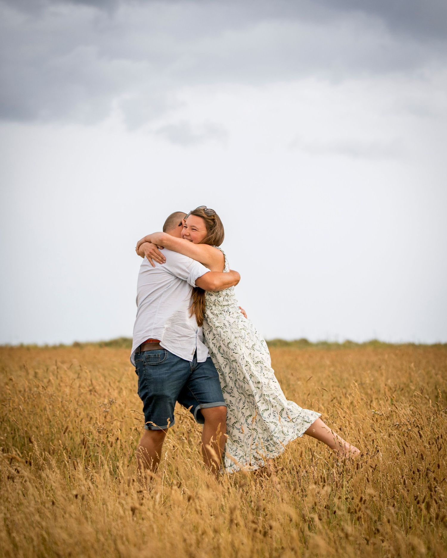 Playful interaction in golden wheat field under dramatic sky.