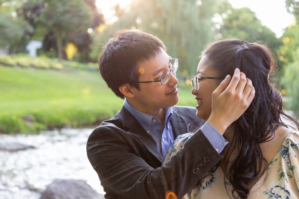 A close up shot of a couple where the guy is gently placing her hair behind her ear