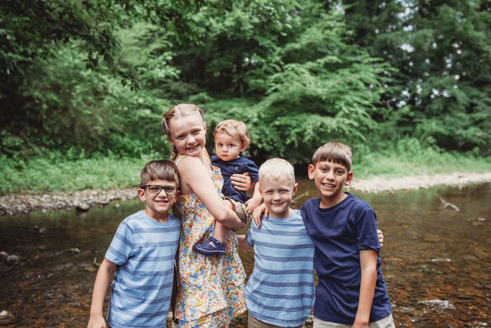 Children playing and smiling together in shallow creek water.
