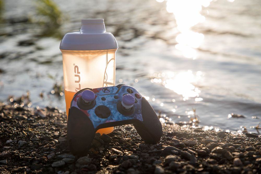 Produktfoto LevlUp Becher steht mit Controller am Strand