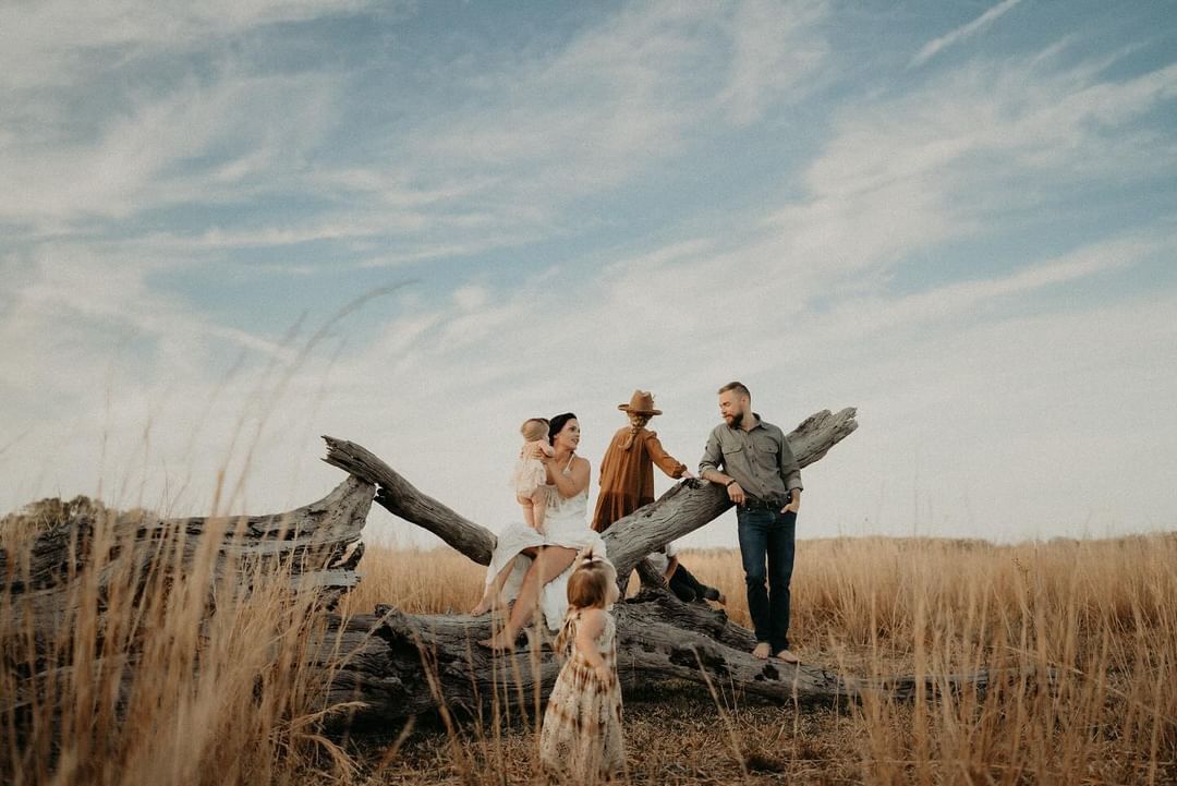 Group walking through a field of tall grass under bright blue skies.