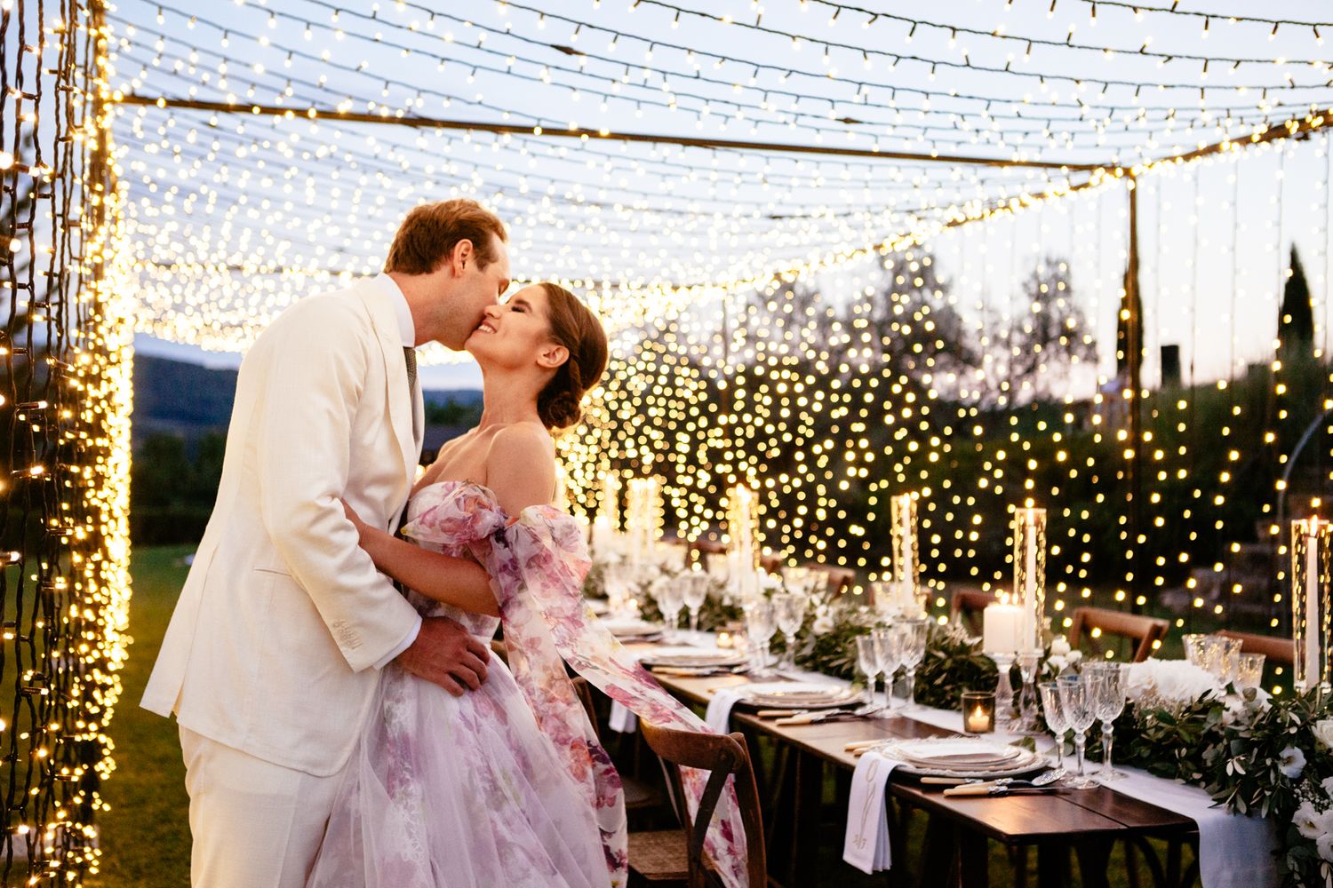 wedding couple kiss under a canopy of fairy lights