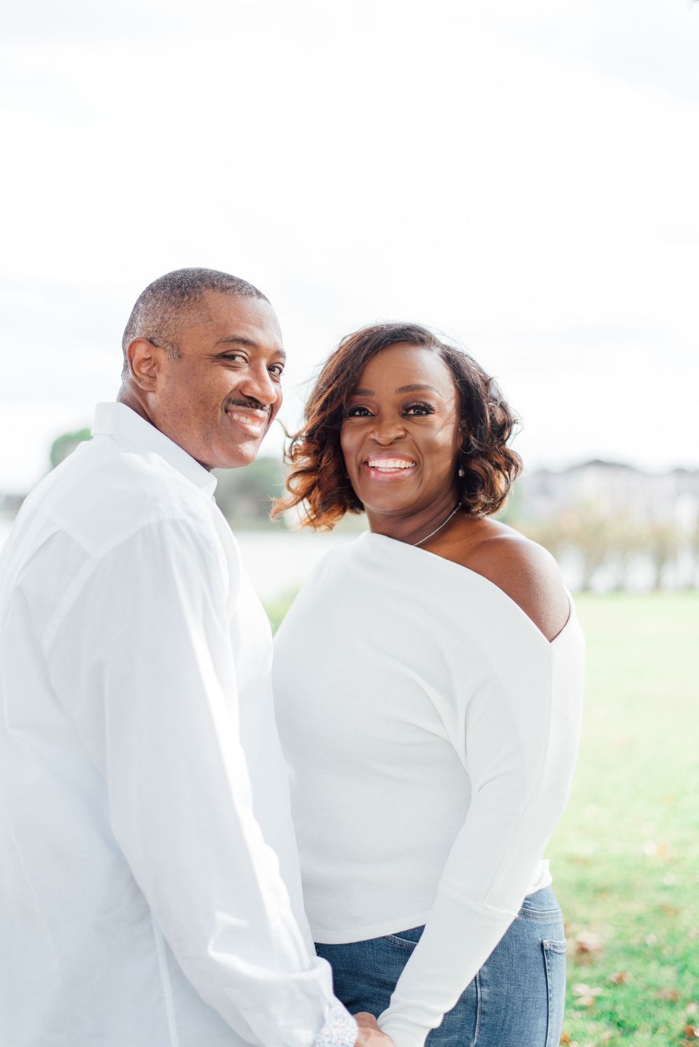 Couple in matching white tops smiles together in outdoor setting.