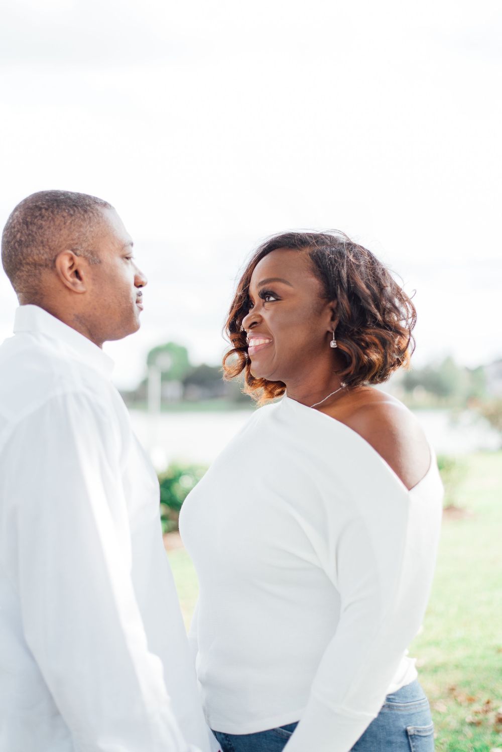 Couple in white clothing shares intimate moment while posing outdoors.