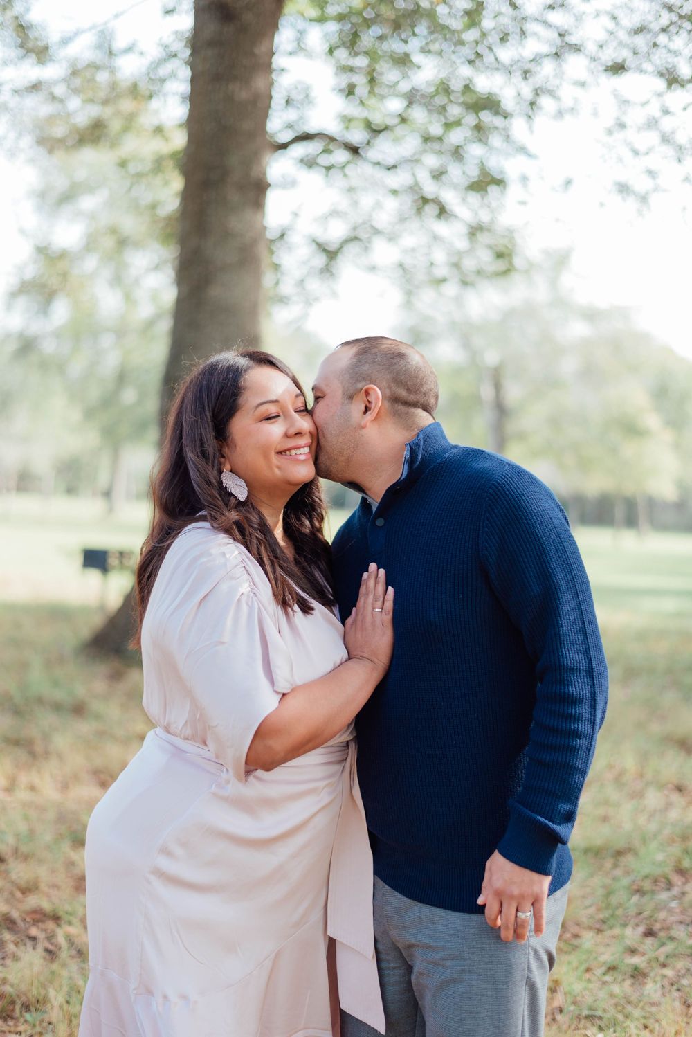 A couple sharing an intimate moment outdoors wearing white and navy as they embrace in a romantic photoshoot.