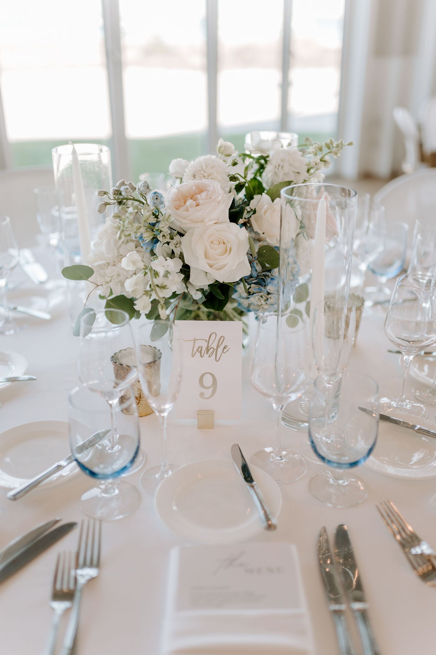 Elegant wedding table settings with white floral centerpieces and table numbers.