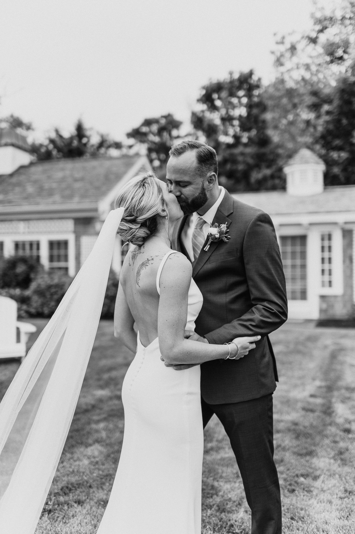 A black and white wedding portrait capturing a tender moment against a traditional building backdrop.