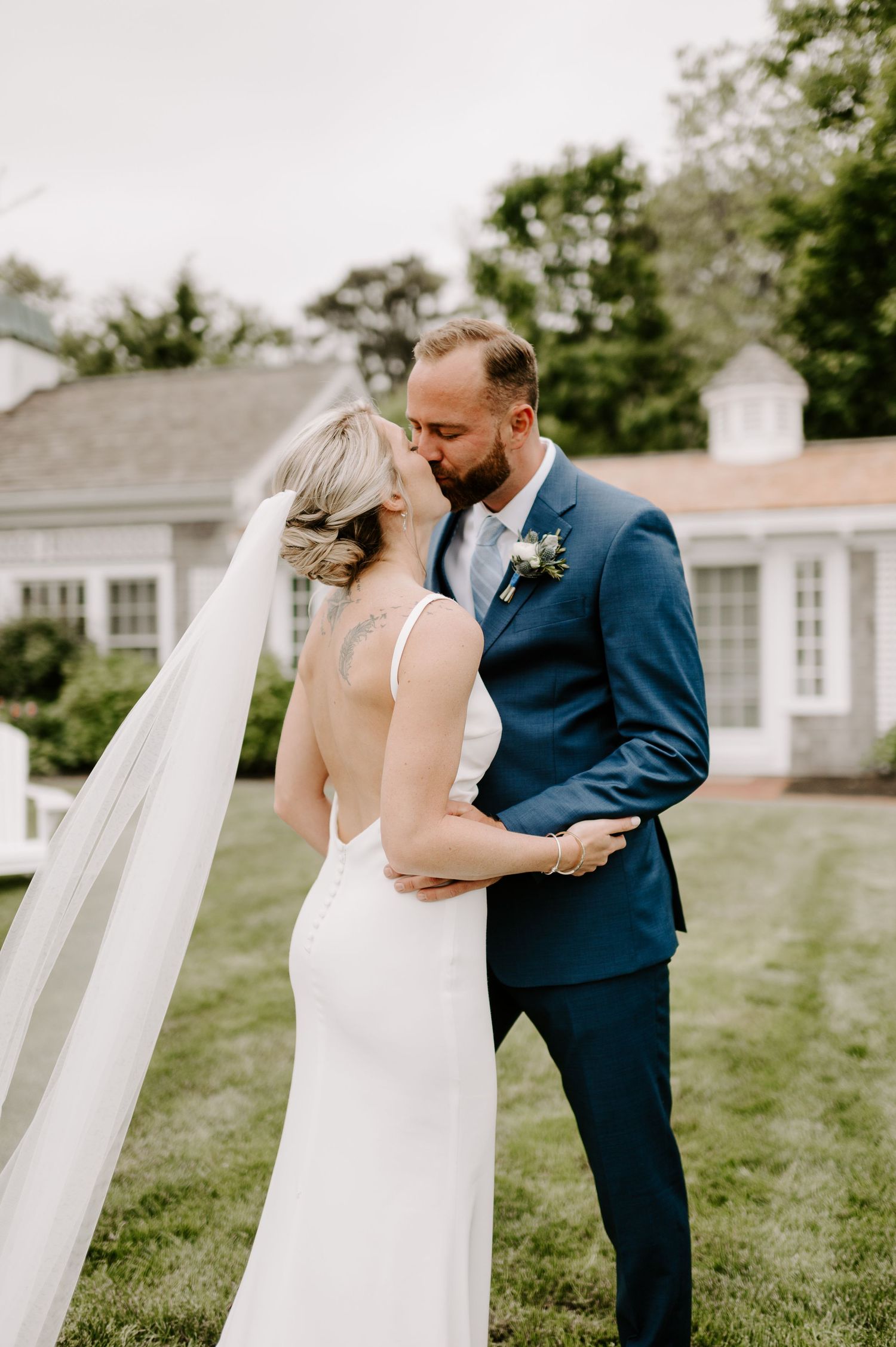 An intimate wedding portrait showcasing a sleek white dress and navy suit against classic architecture.