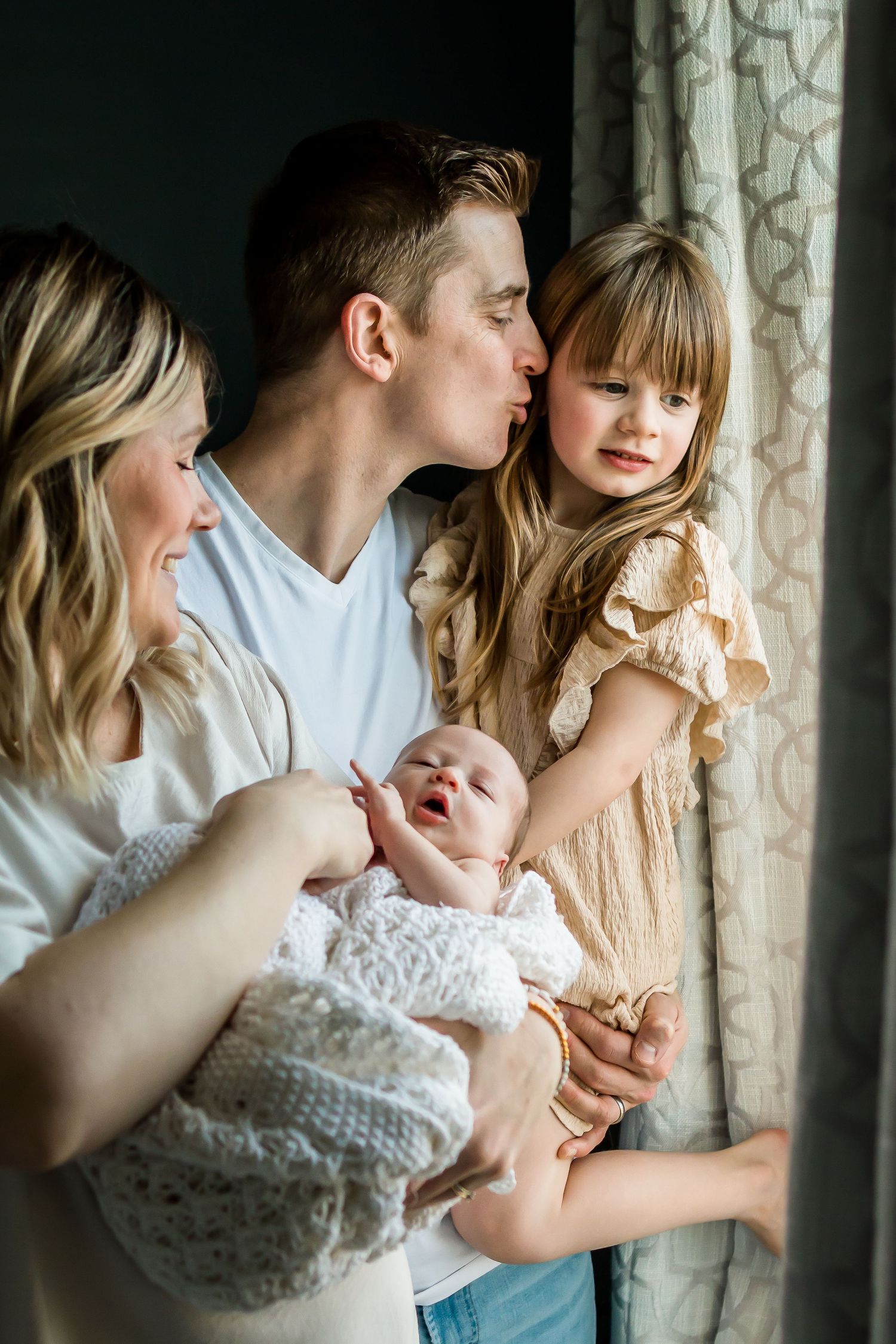 Authentic family moment with new baby captured by Calgary photographer using natural window light at home.