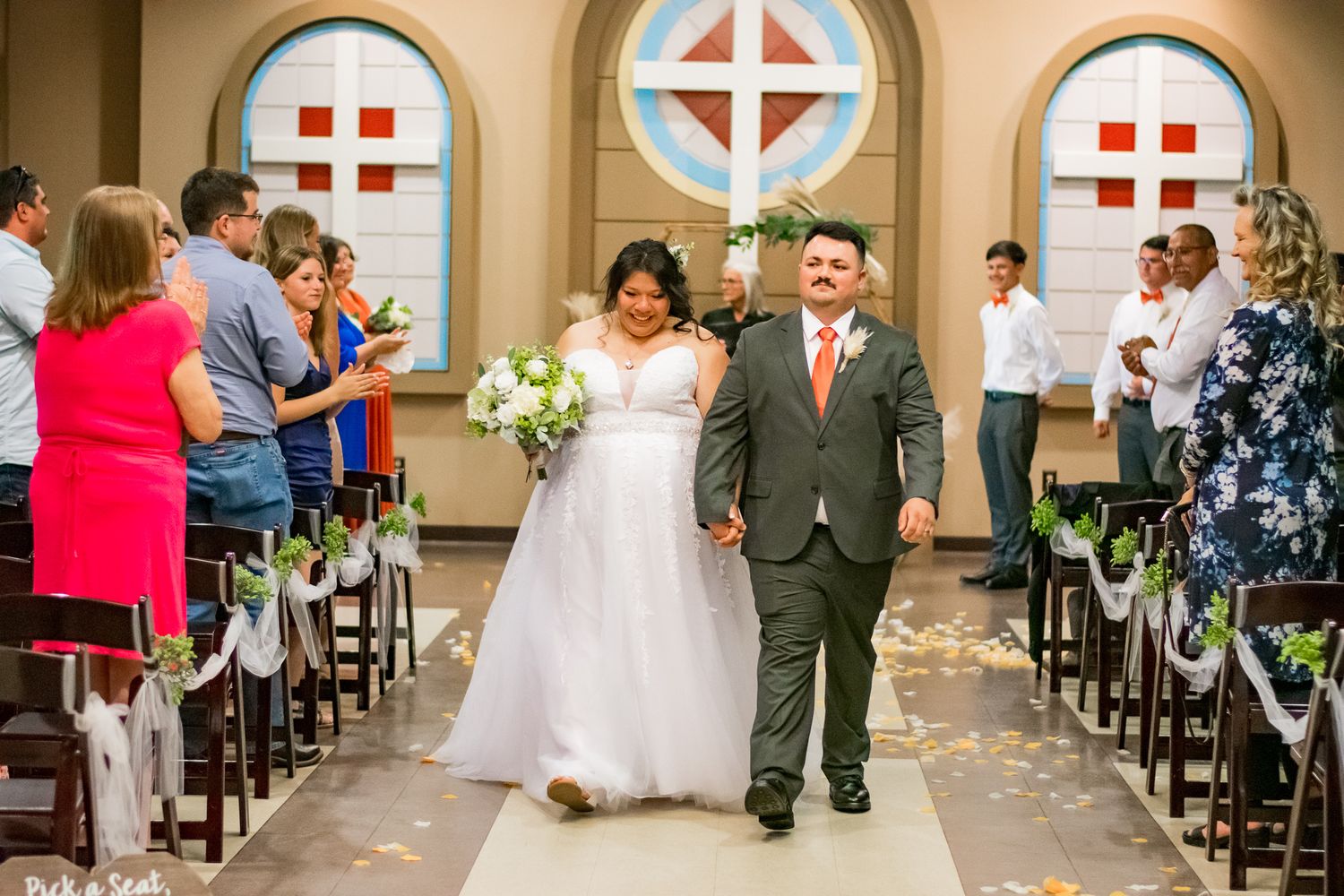 Newlyweds walk down the aisle together after their wedding ceremony in a church.