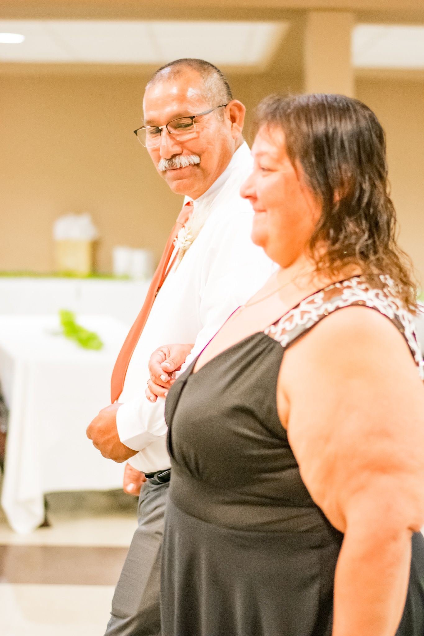 Formal event attendees smiling and enjoying themselves at an indoor celebration.