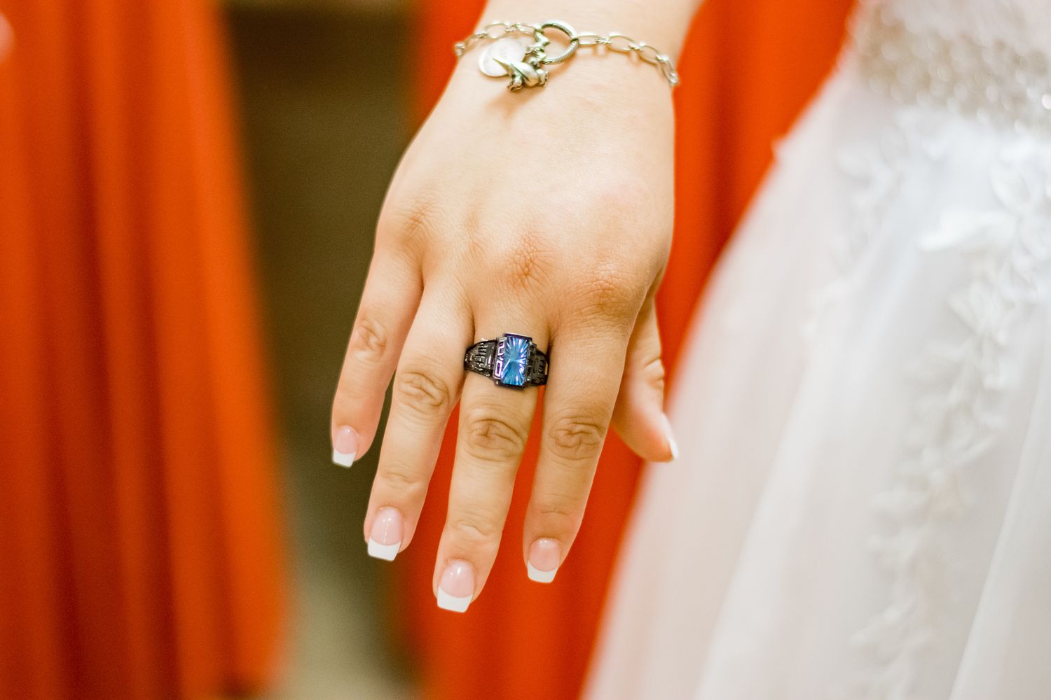 A close-up of an elegant blue stone ring and bracelet on a manicured hand.