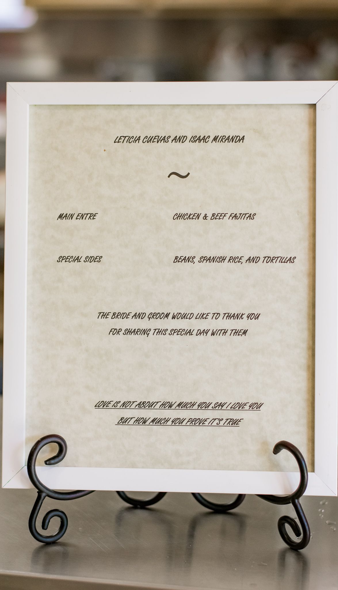 Wedding program displayed on white paper in a decorative stand showing ceremony details and special thanks.