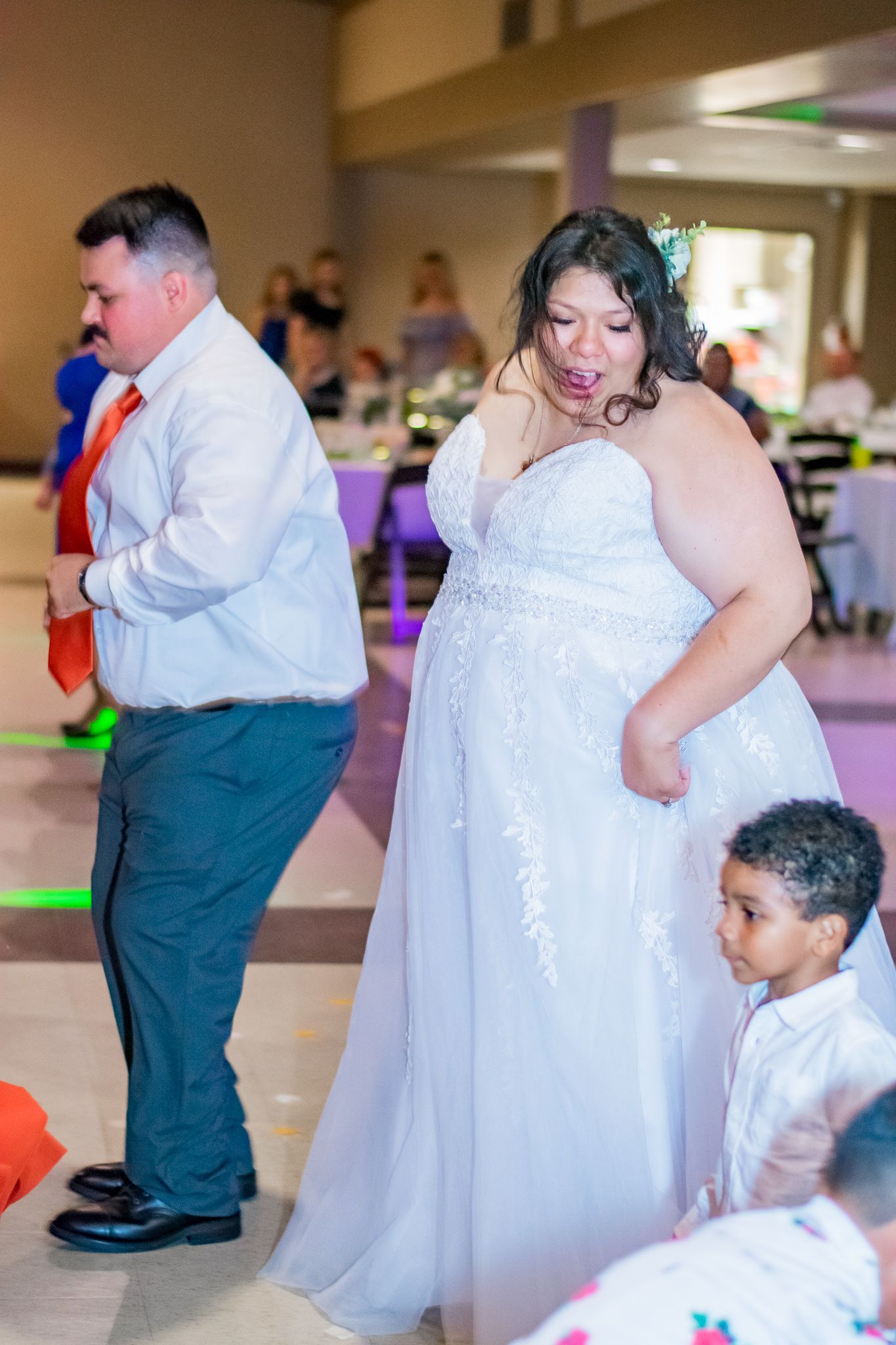 Wedding celebration in a reception hall with guests in formal attire.