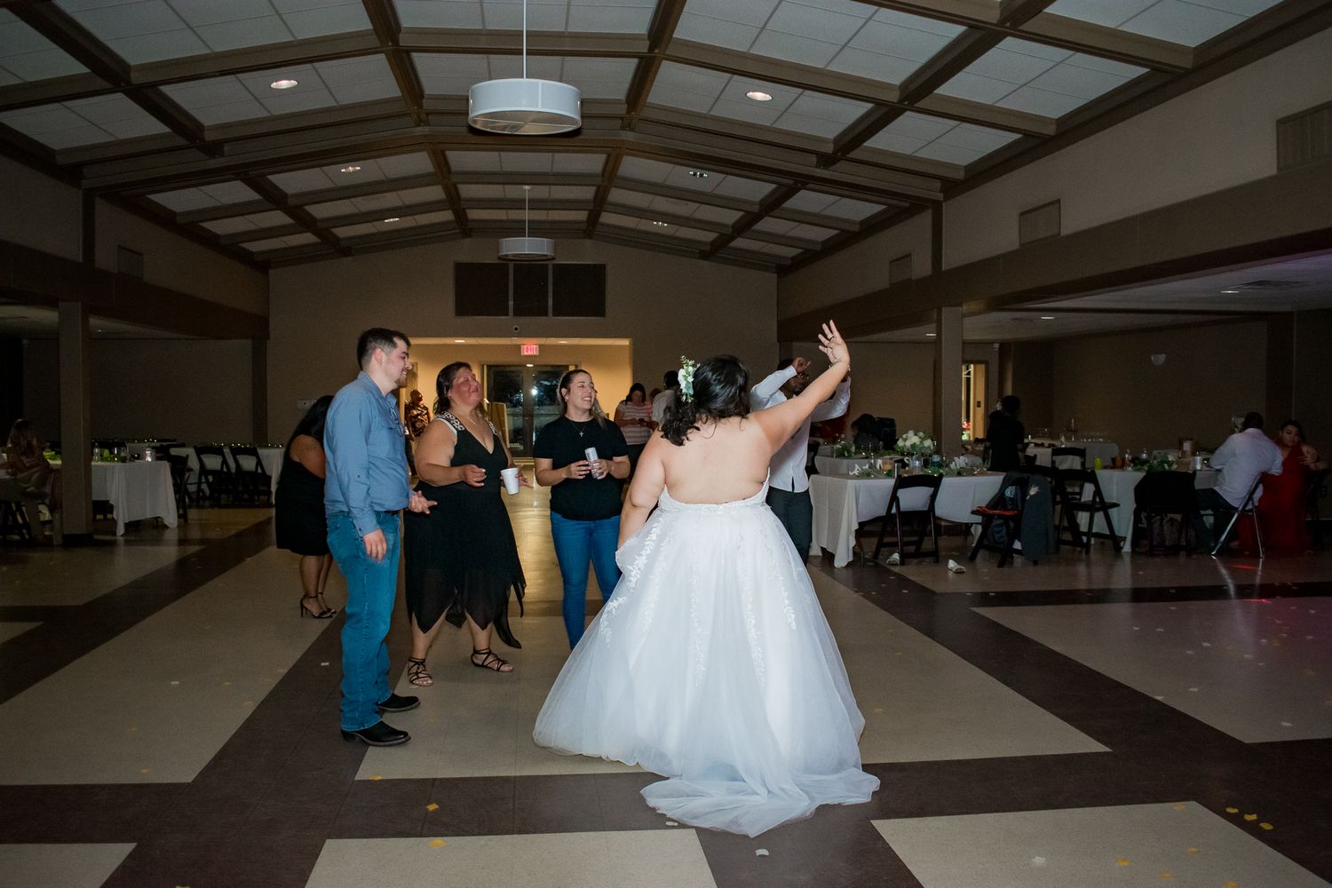Joyful dancing at a wedding reception in a venue with wooden beam ceiling.