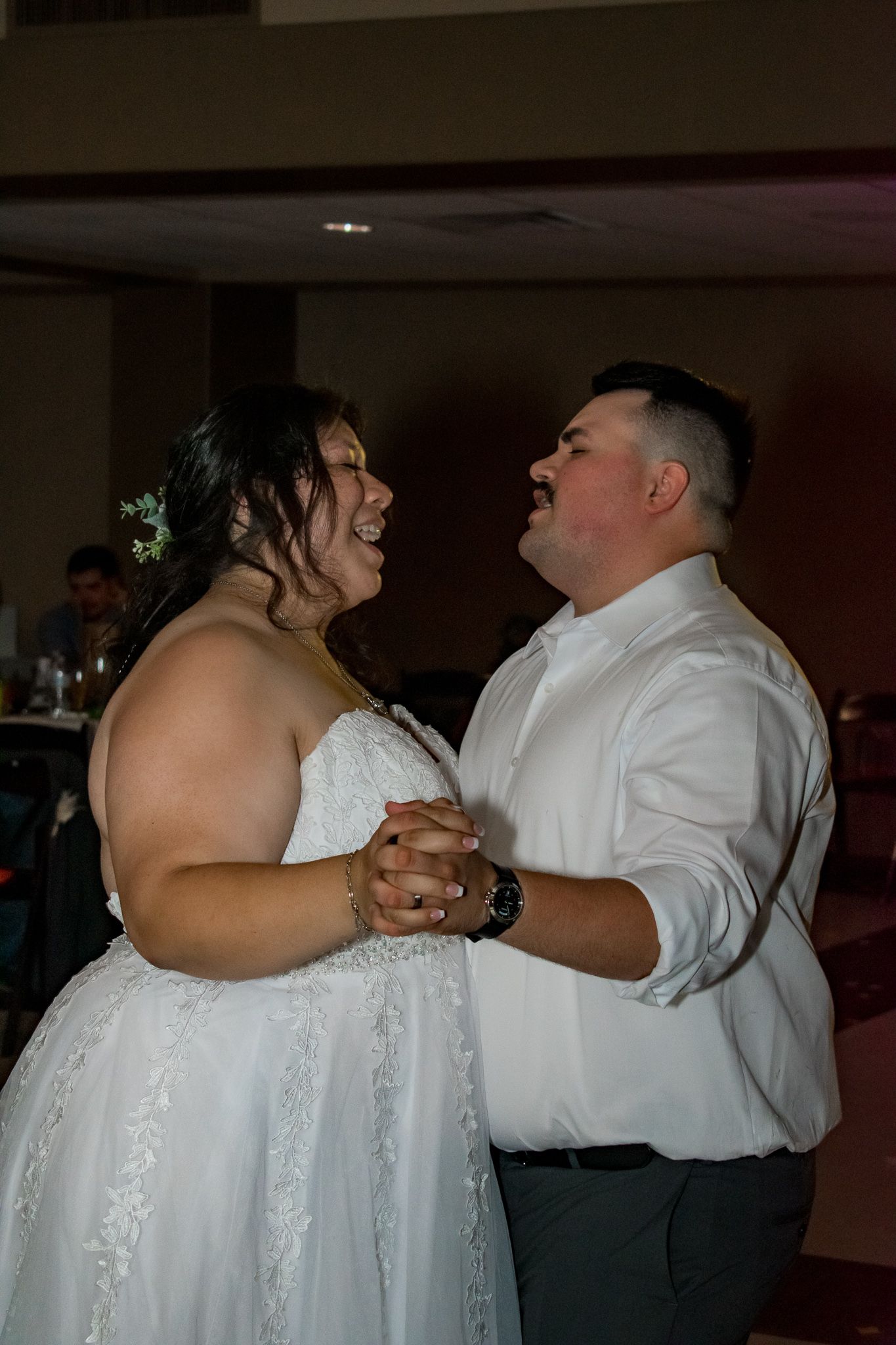 A couple shares their first dance together at their wedding reception in a ballroom.