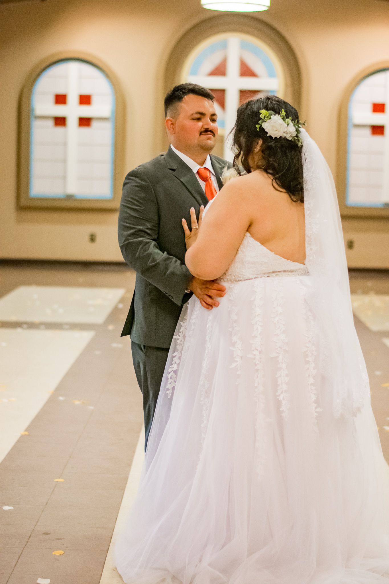 Wedding ceremony in church with stained glass windows and elegant lighting.