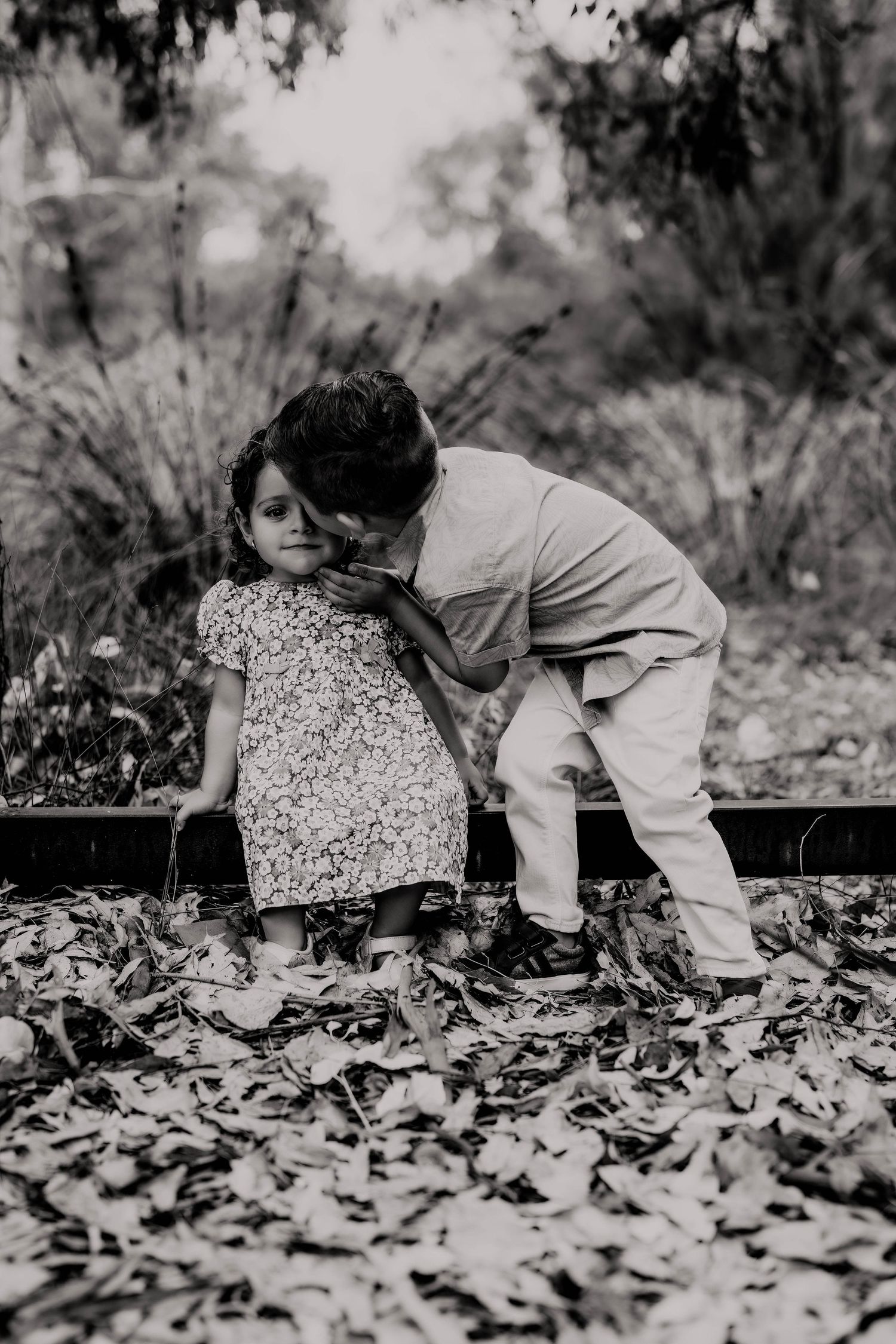 Black and white photo of a person crawling through autumn leaves in the woods.