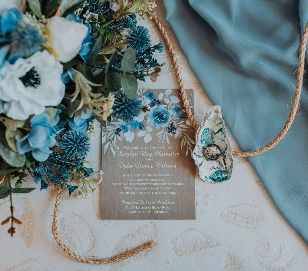 Rustic wedding invitation for Kayelyn and Tyler with blue floral bouquet and teal ribbon.