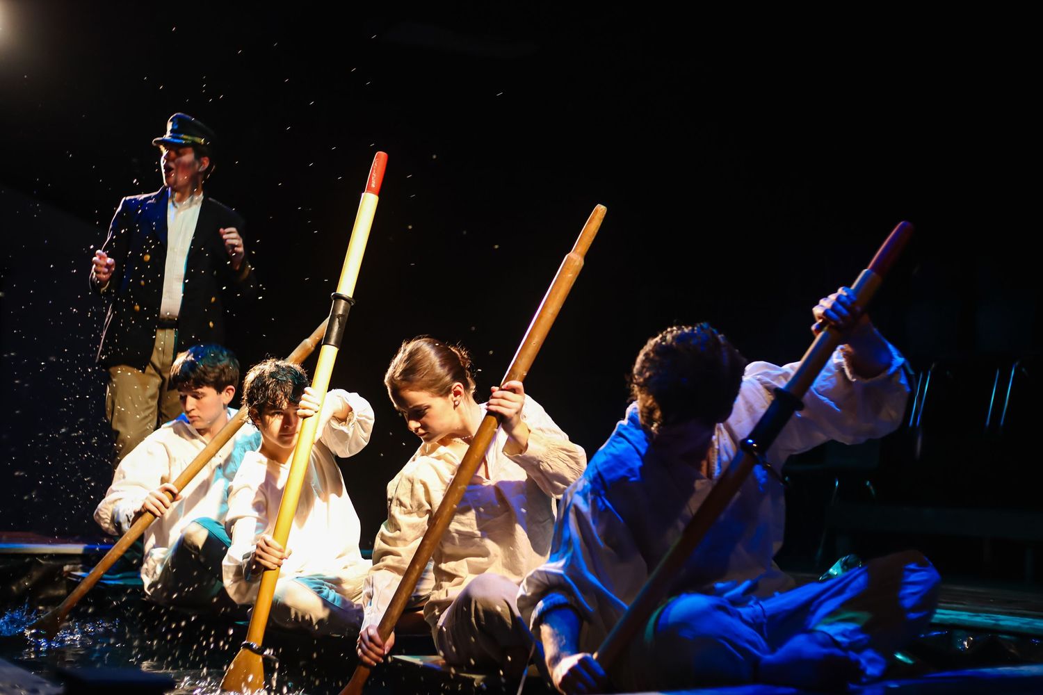 Actors from Metamorphoses using oars in a pool