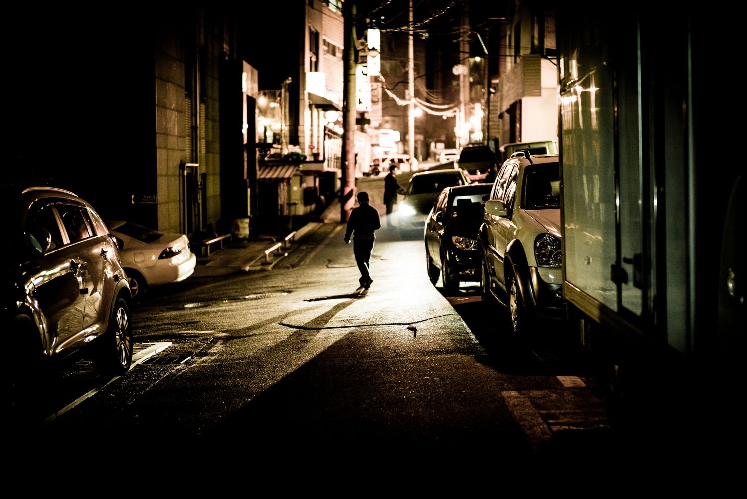 Man lit by car light in back street of Soul South Korea