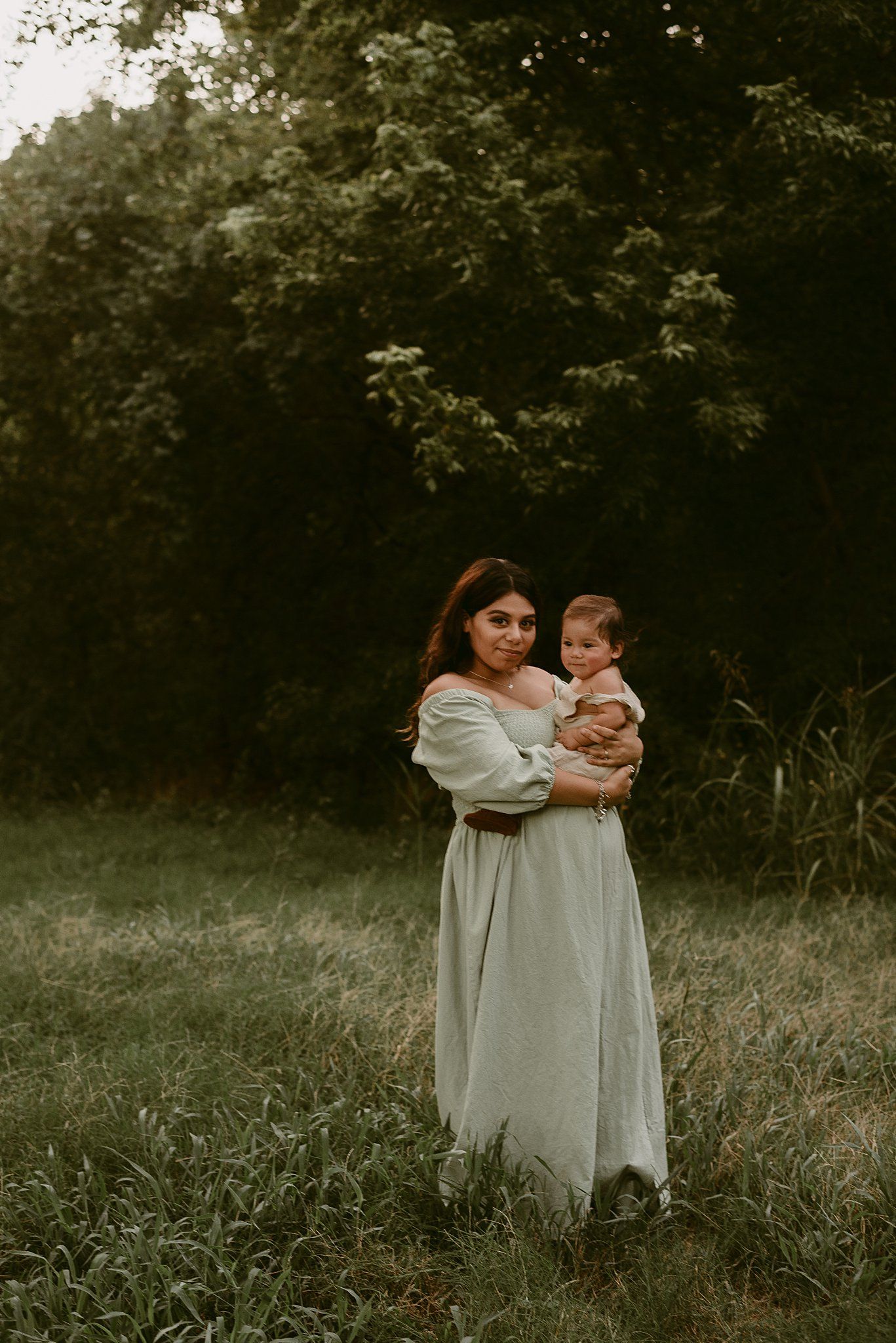 A tender moment captured in the evening light shows two figures in a serene outdoor setting.