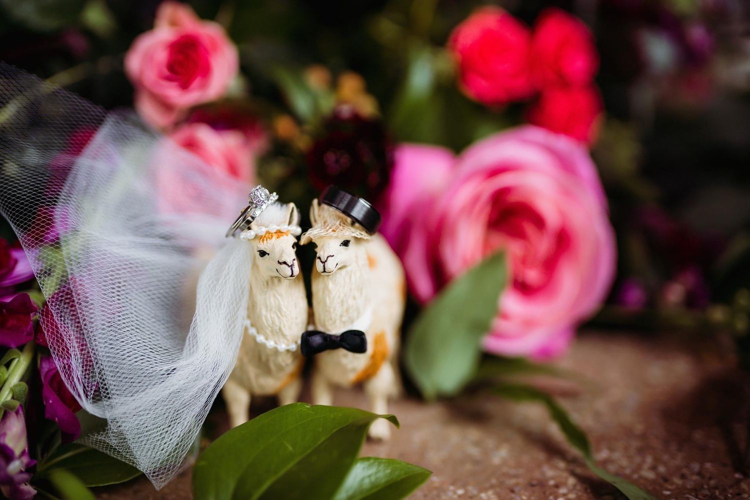 Decorative ceramic cats wearing veils surrounded by pink roses and tulle.