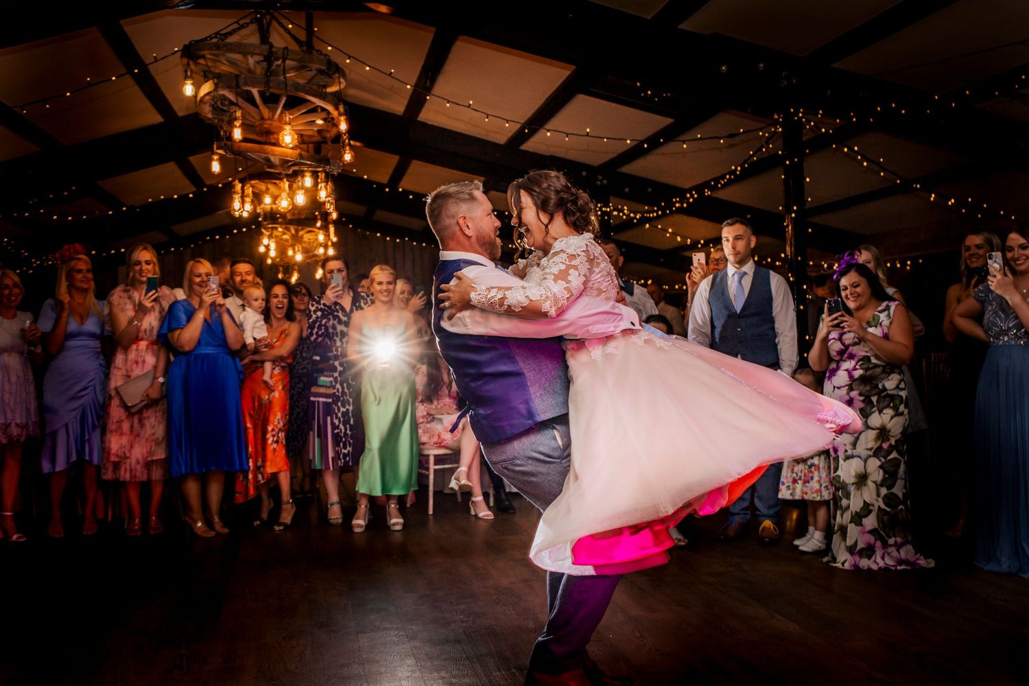 dramatic first dance photograph as the bride and groom spin round under lights and vaulted ceilin at deighton lodge york