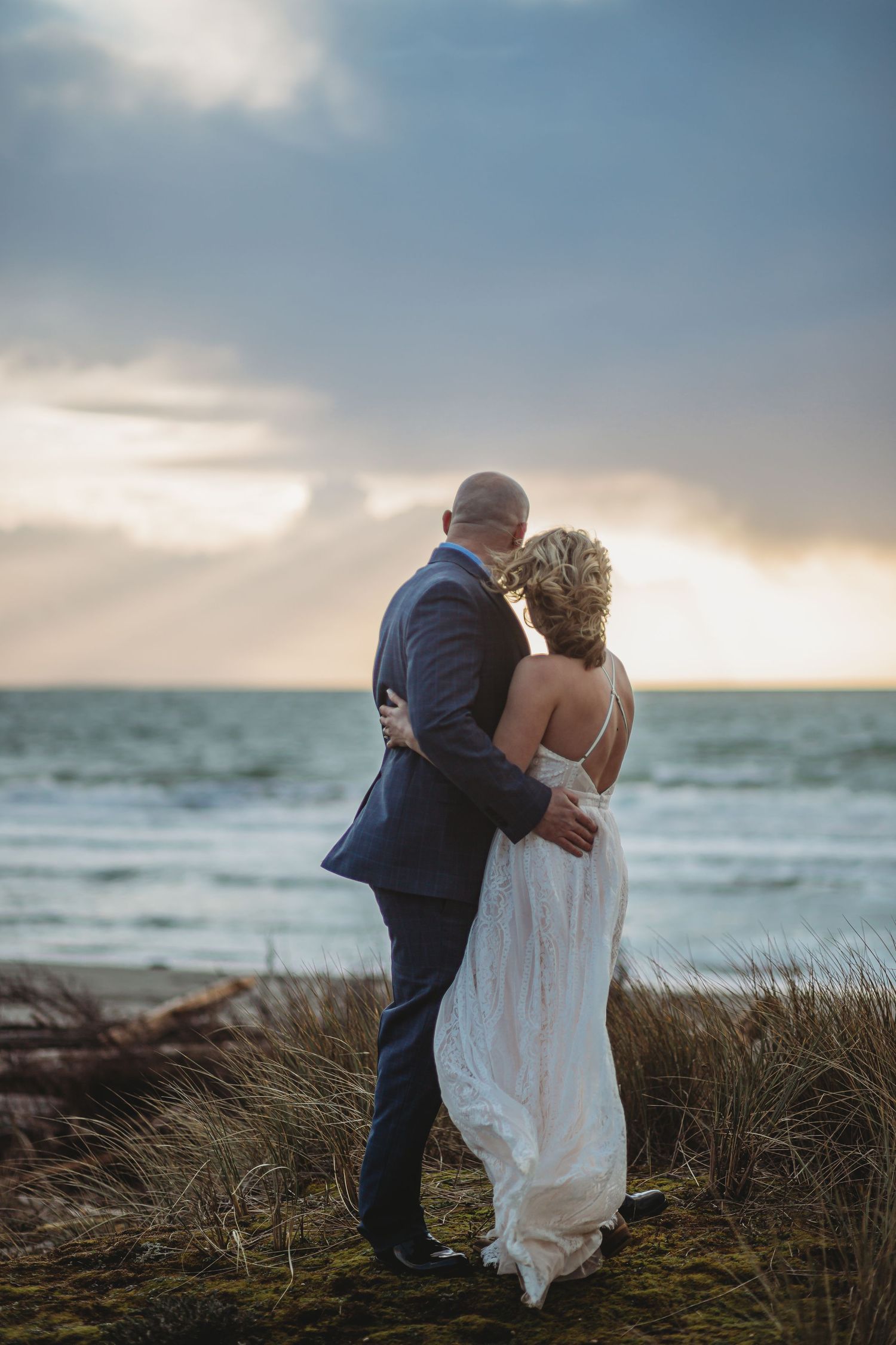 A bride and groom face the ocean sunset on their elopement day.