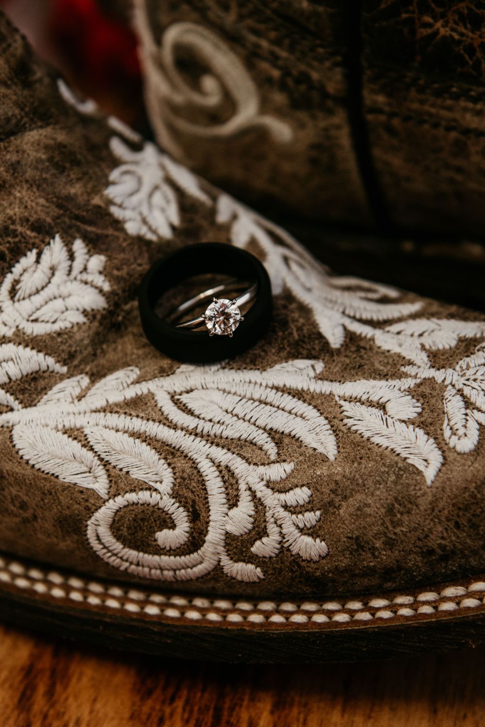 Wedding rings resting on embroidered cowboy boots for a rustic country wedding detail shot.