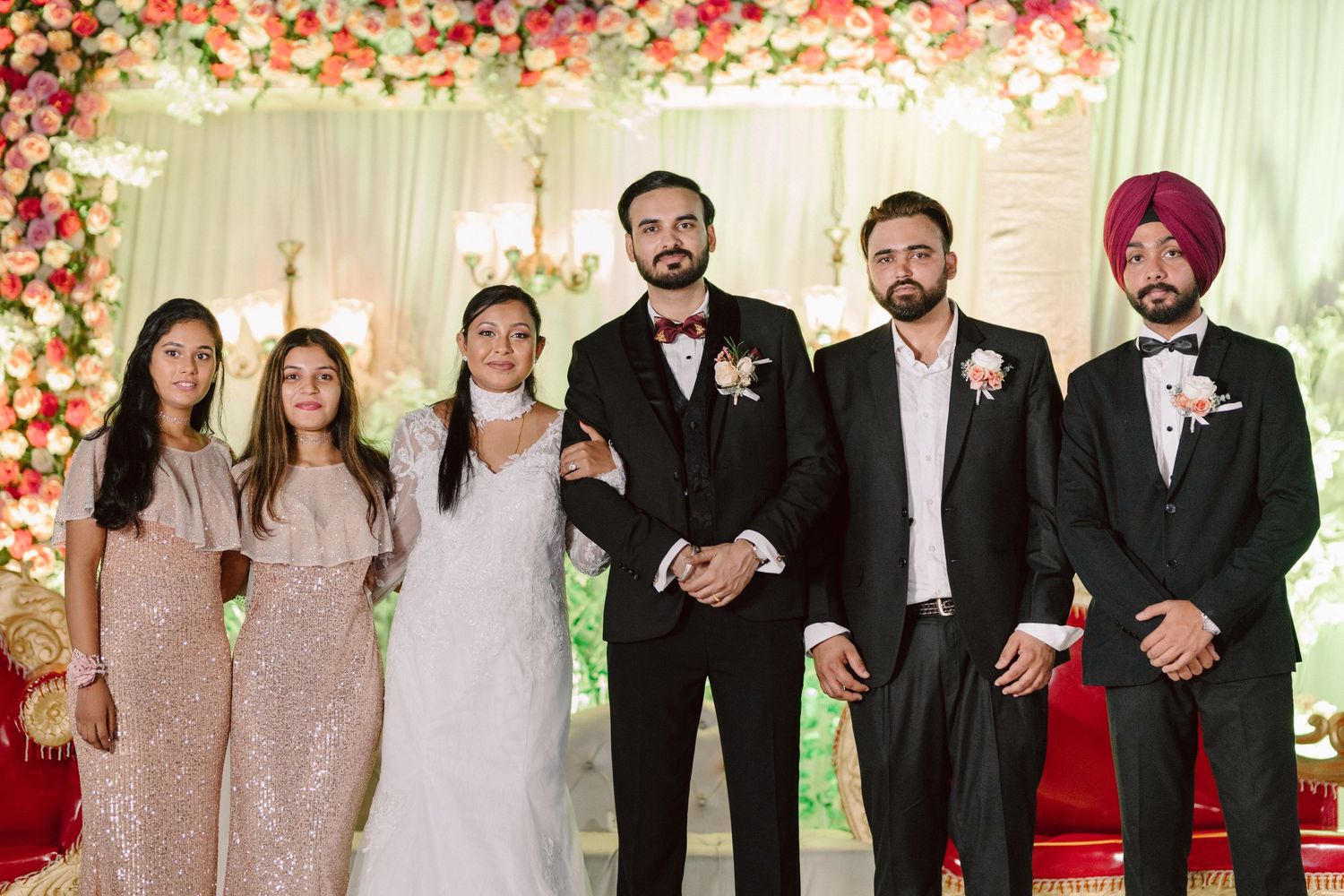 Wedding party posing together with bridesmaids in blush dresses and groomsmen in black suits.