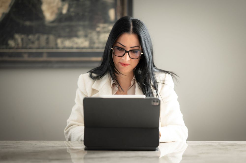 Professional working on laptop in home office setting with neutral background.