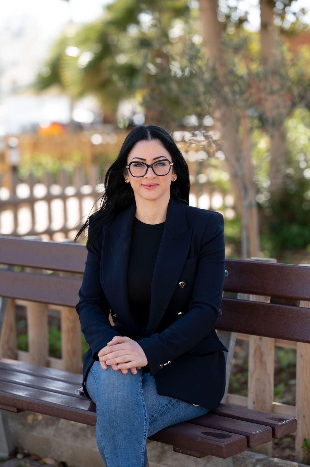 Professional portrait series taken outdoors on a wooden bench with trees in the background.