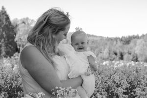 Black and white portrait of mother and baby in blooming wildflower field.
