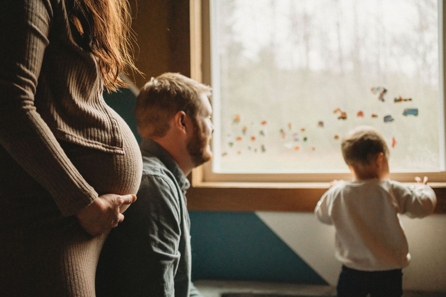 A family looks out a window together with decorative stickers while sharing an intimate moment.