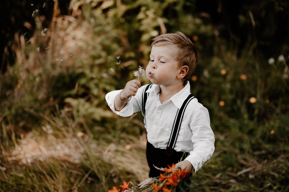 Child playing outdoors in autumn setting with fallen leaves and natural backdrop.