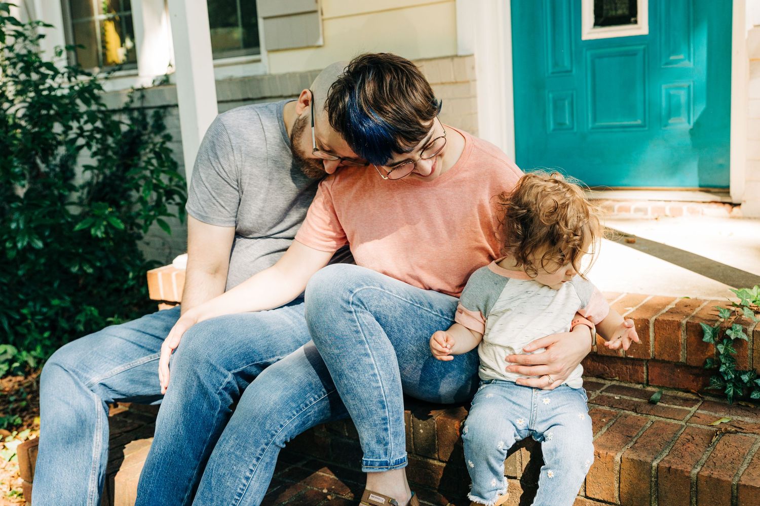 A family of three sit on their front porch of their Charlotte home