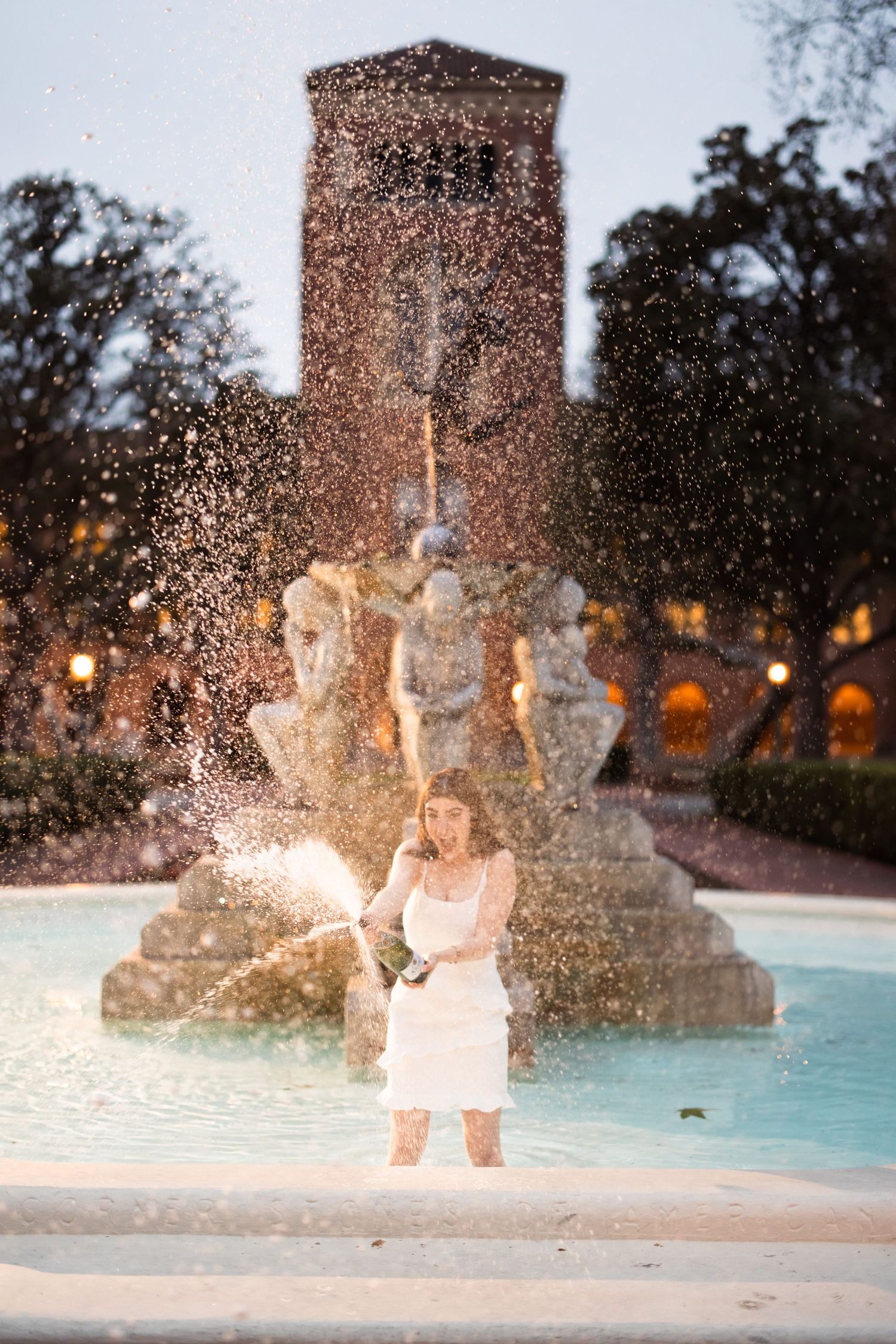 A magic sparkler moment captured at a fountain during twilight with warm glowing lights in the background.