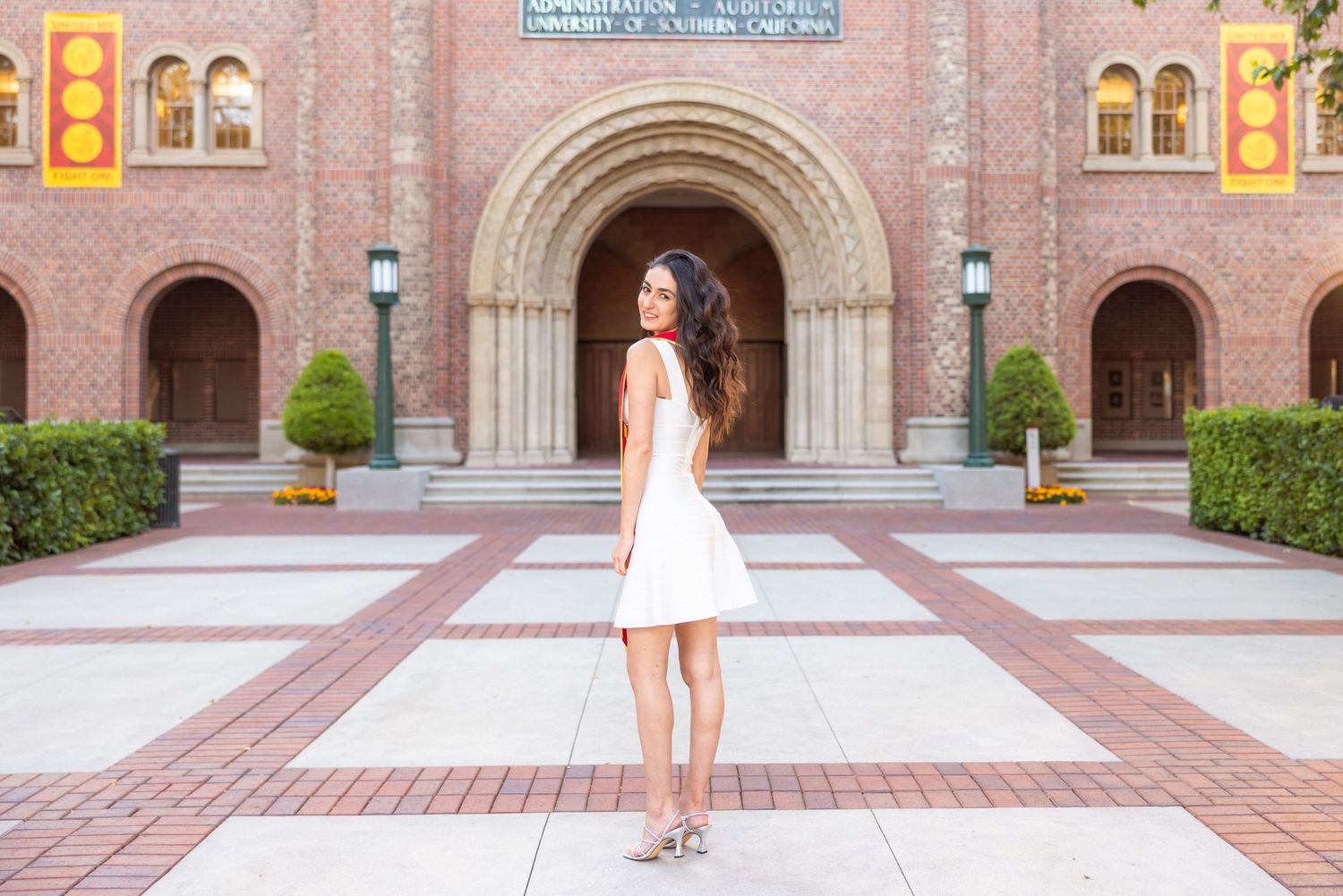 White dress outfit photographed in front of ornate brick archways and architecture.