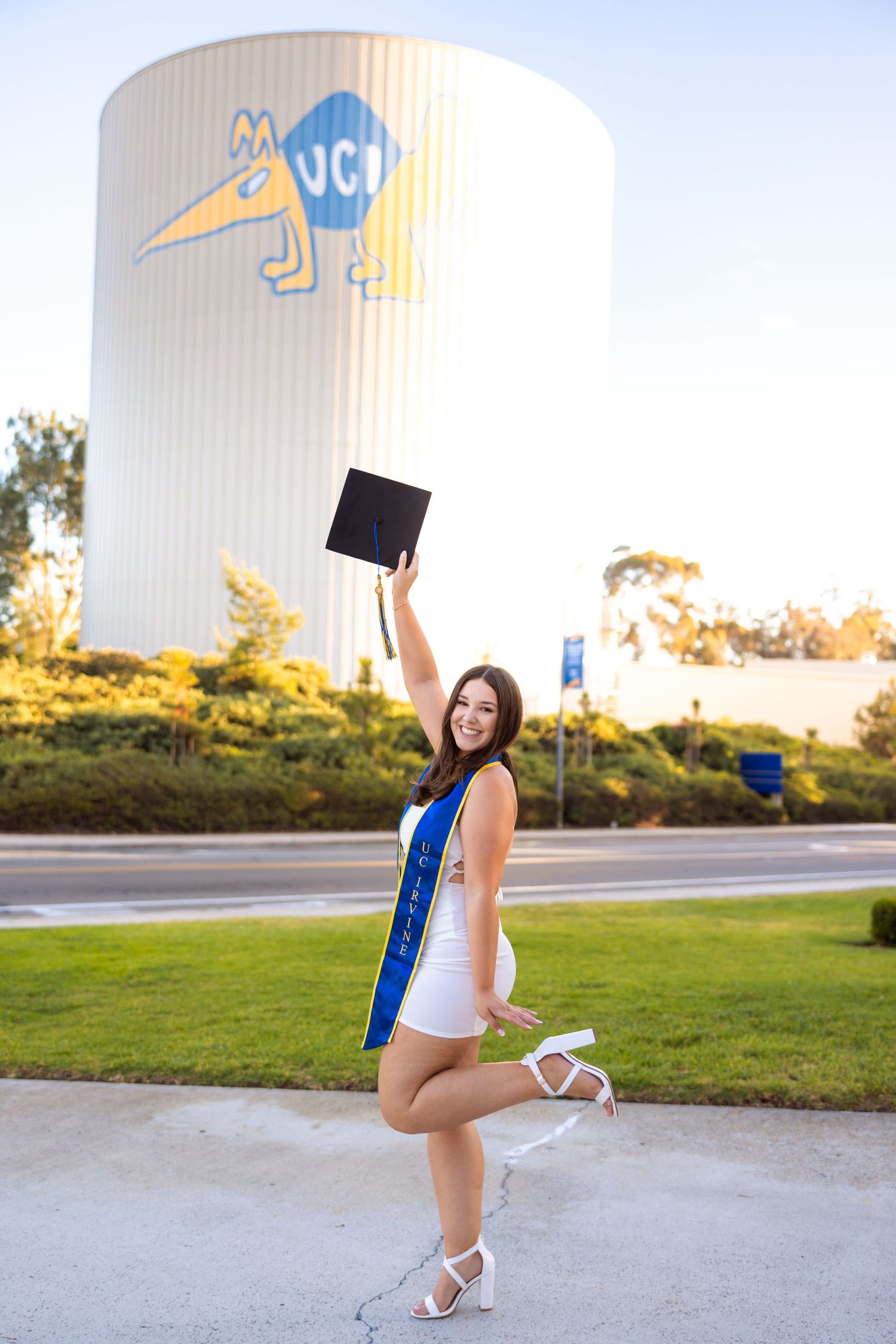 Graduate celebrating with cap toss in front of iconic UCI water tower.