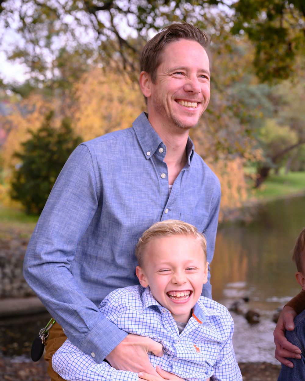 Candid outdoor family portrait capturing joyful laughter in autumn setting.