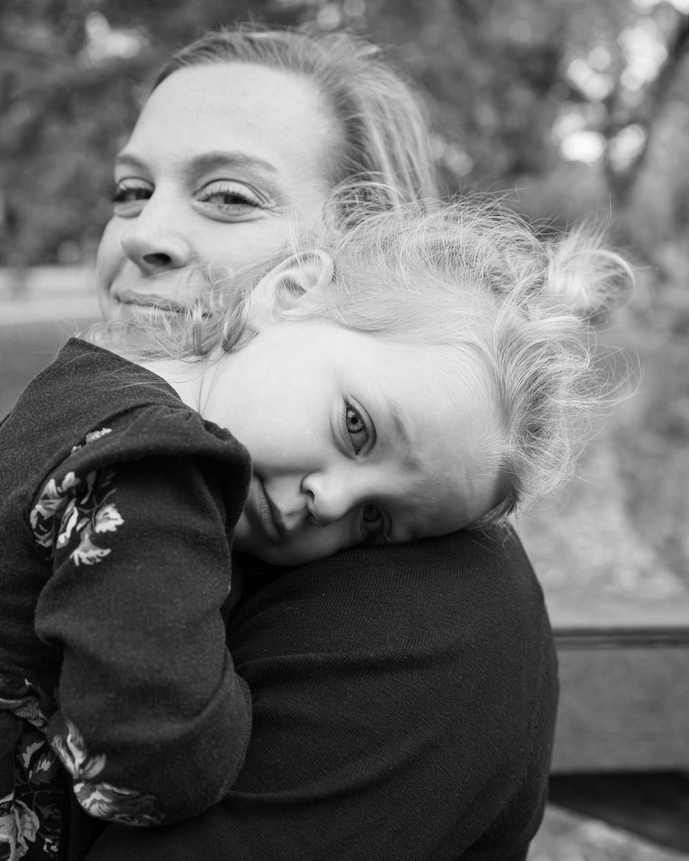 Black and white portrait capturing intimate parental moment outdoors.